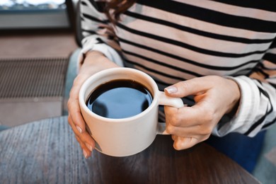 Photo of Businesswoman having coffee break at wooden table in cafe, closeup