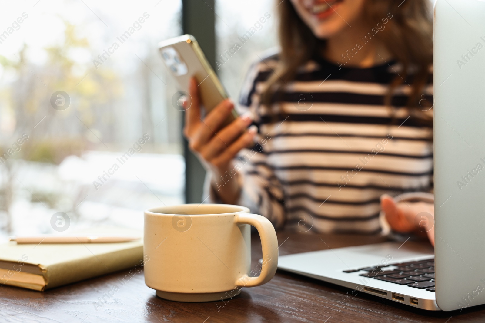 Photo of Woman with smartphone having coffee break at wooden table in cafe, closeup