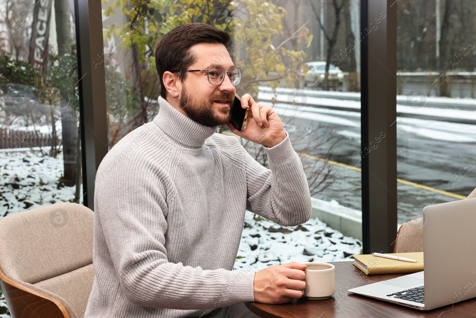 Photo of Businessman talking on smartphone during coffee break in cafe