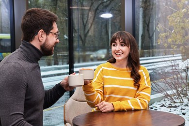 Photo of Happy colleagues talking during coffee break at wooden table in cafe