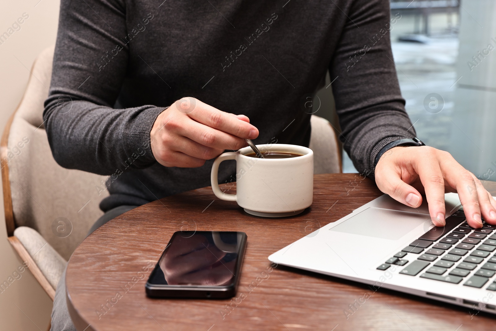 Photo of Businessman having coffee break at wooden table in cafe, closeup