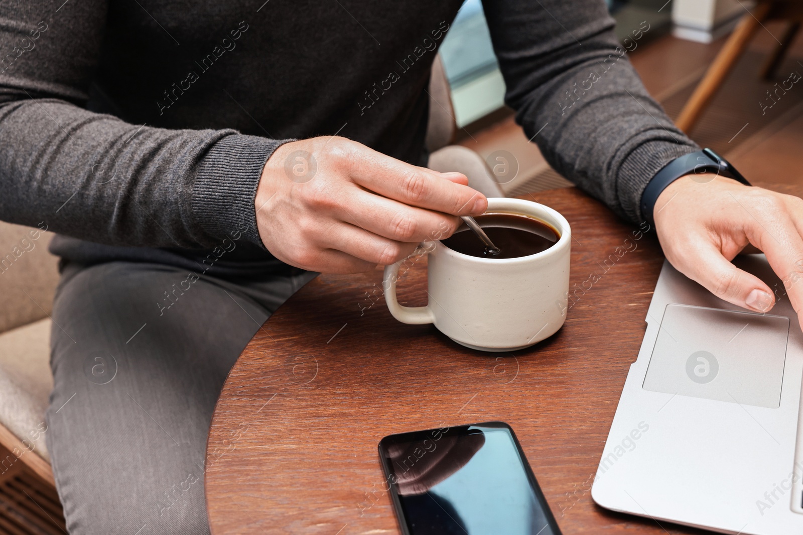 Photo of Businessman having coffee break at wooden table in cafe, closeup