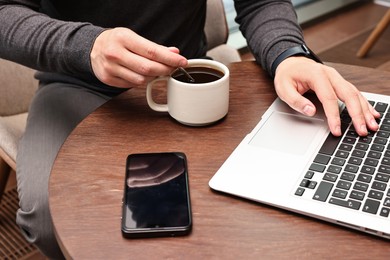 Photo of Businessman having coffee break at wooden table in cafe, closeup