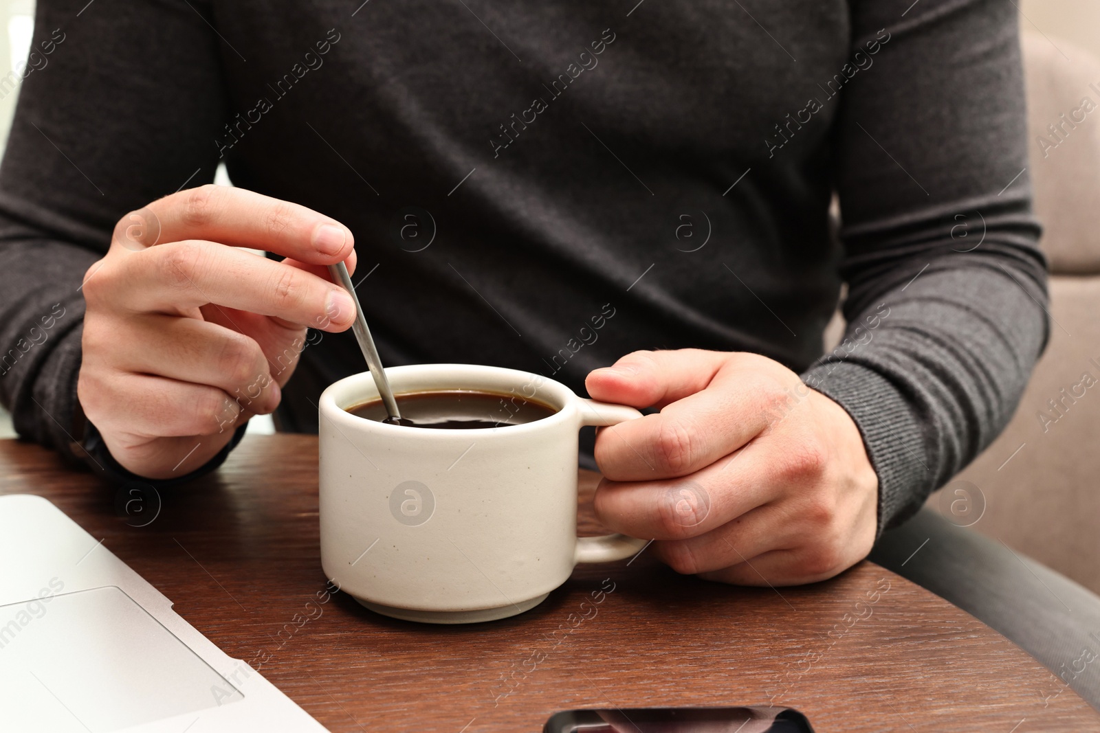 Photo of Man having coffee break at wooden table in cafe, closeup