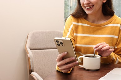 Photo of Smiling woman with smartphone having coffee break in cafe, closeup. Space for text