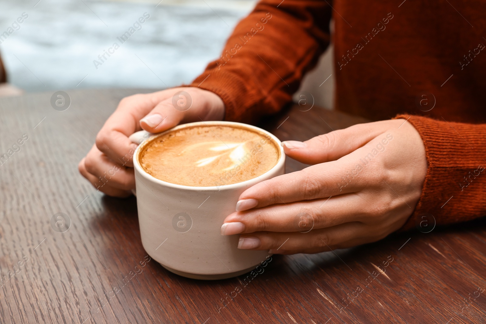 Photo of Woman having coffee break at wooden table in cafe, closeup