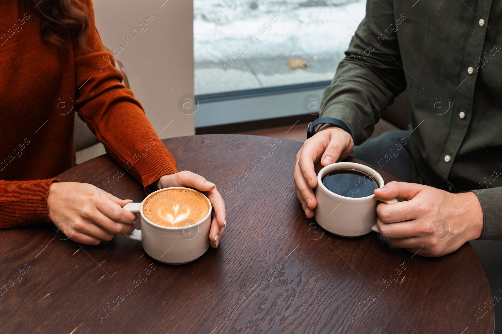 Photo of Colleagues having coffee break at wooden table in cafe, closeup