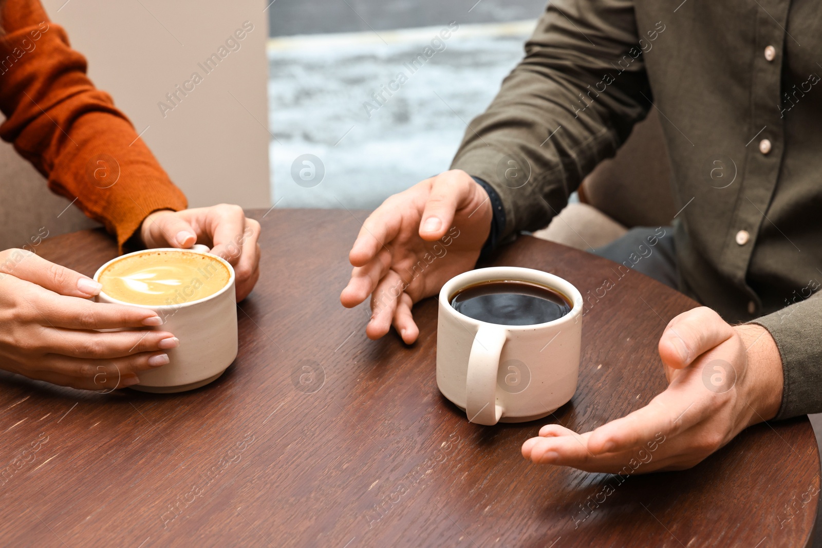 Photo of Colleagues having coffee break at wooden table in cafe, closeup