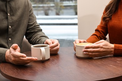 Photo of Colleagues having coffee break at wooden table in cafe, closeup