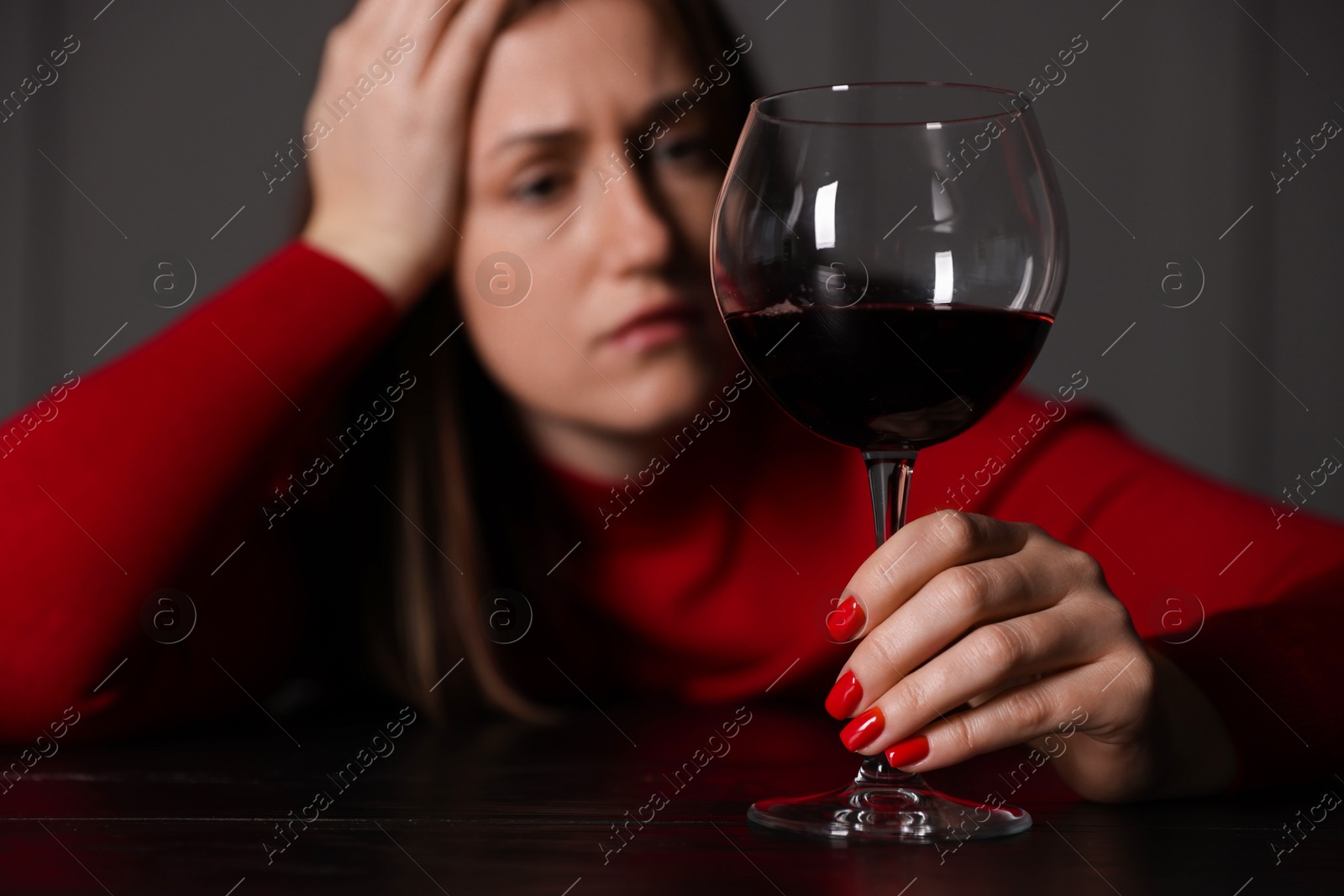 Photo of Alcohol addiction. Woman with glass of red wine at wooden table indoors, selective focus