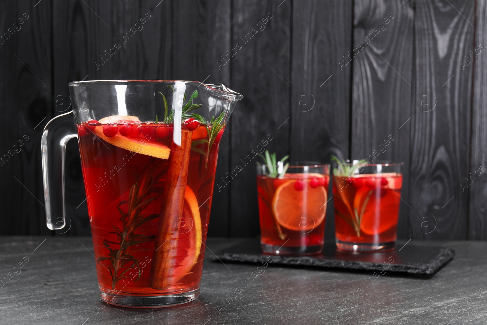 Photo of Delicious punch in jug and glasses on black table