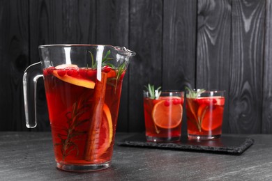 Photo of Delicious punch in jug and glasses on black table