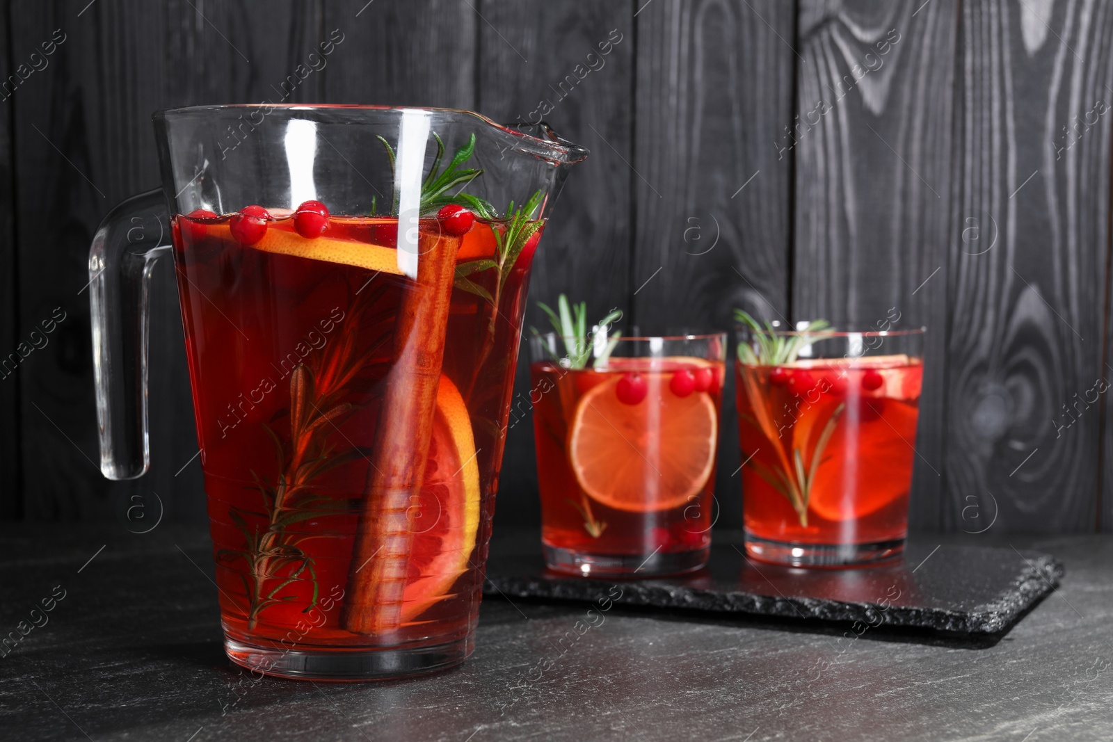 Photo of Delicious punch in jug and glasses on black table