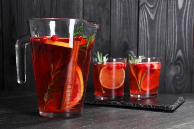 Photo of Delicious punch in jug and glasses on black table