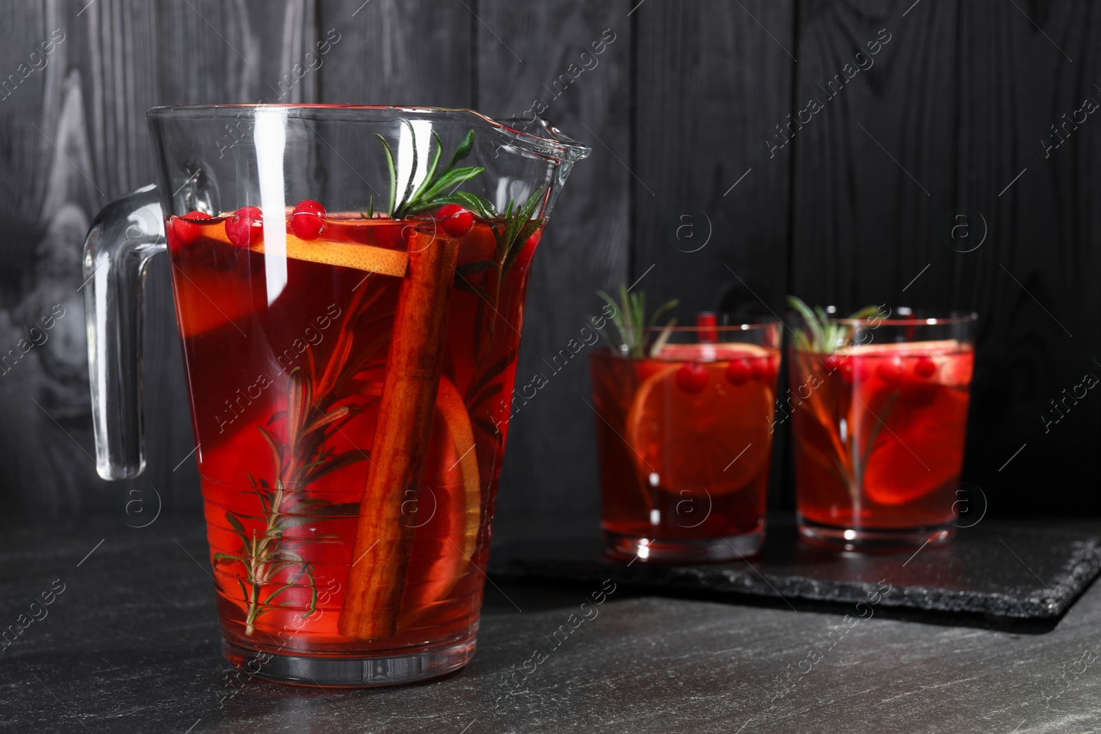 Photo of Delicious punch in jug and glasses on black table