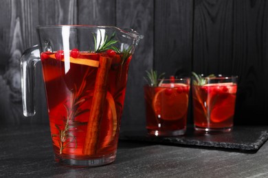 Photo of Delicious punch in jug and glasses on black table