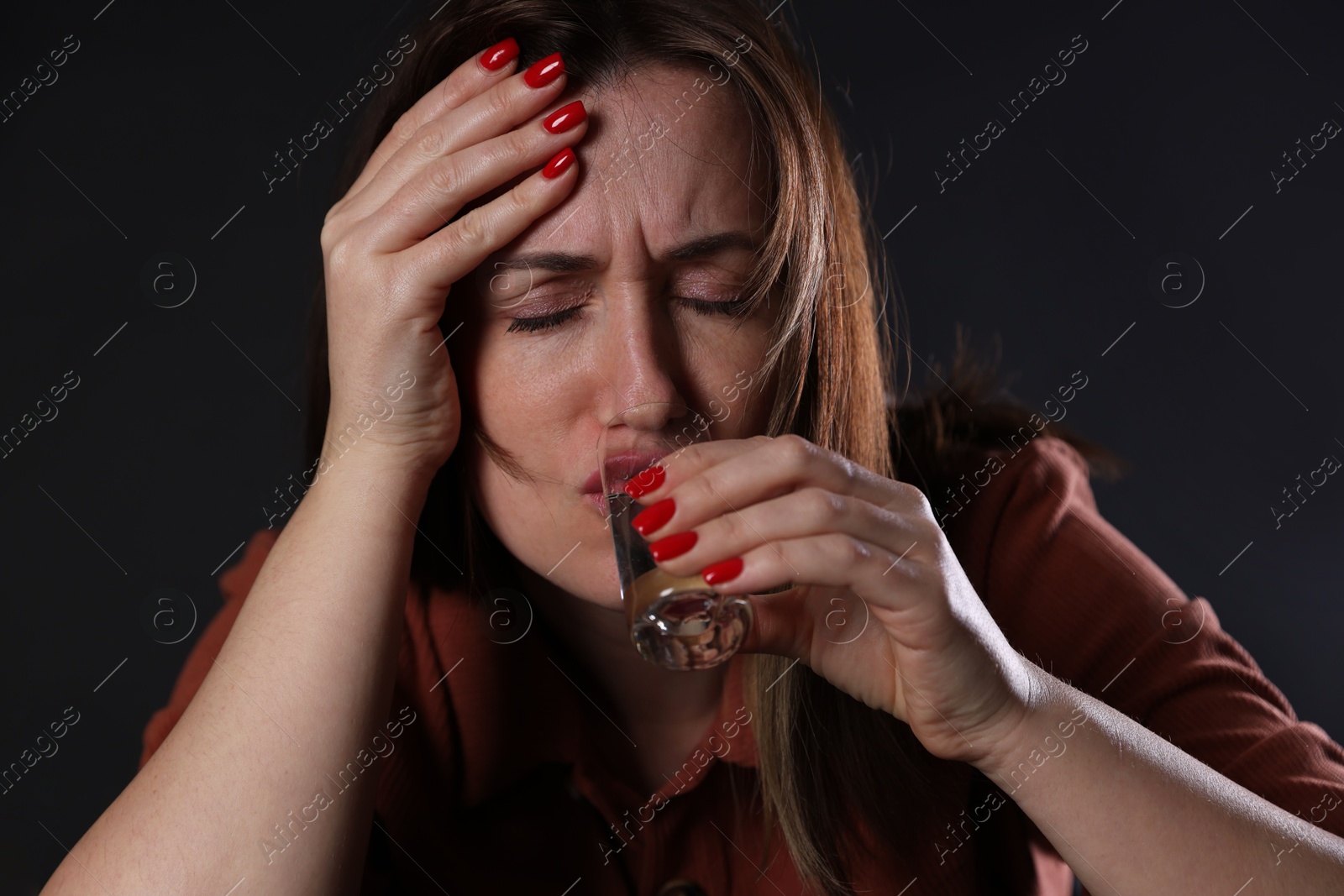 Photo of Alcohol addiction. Miserable woman drinking vodka in dark