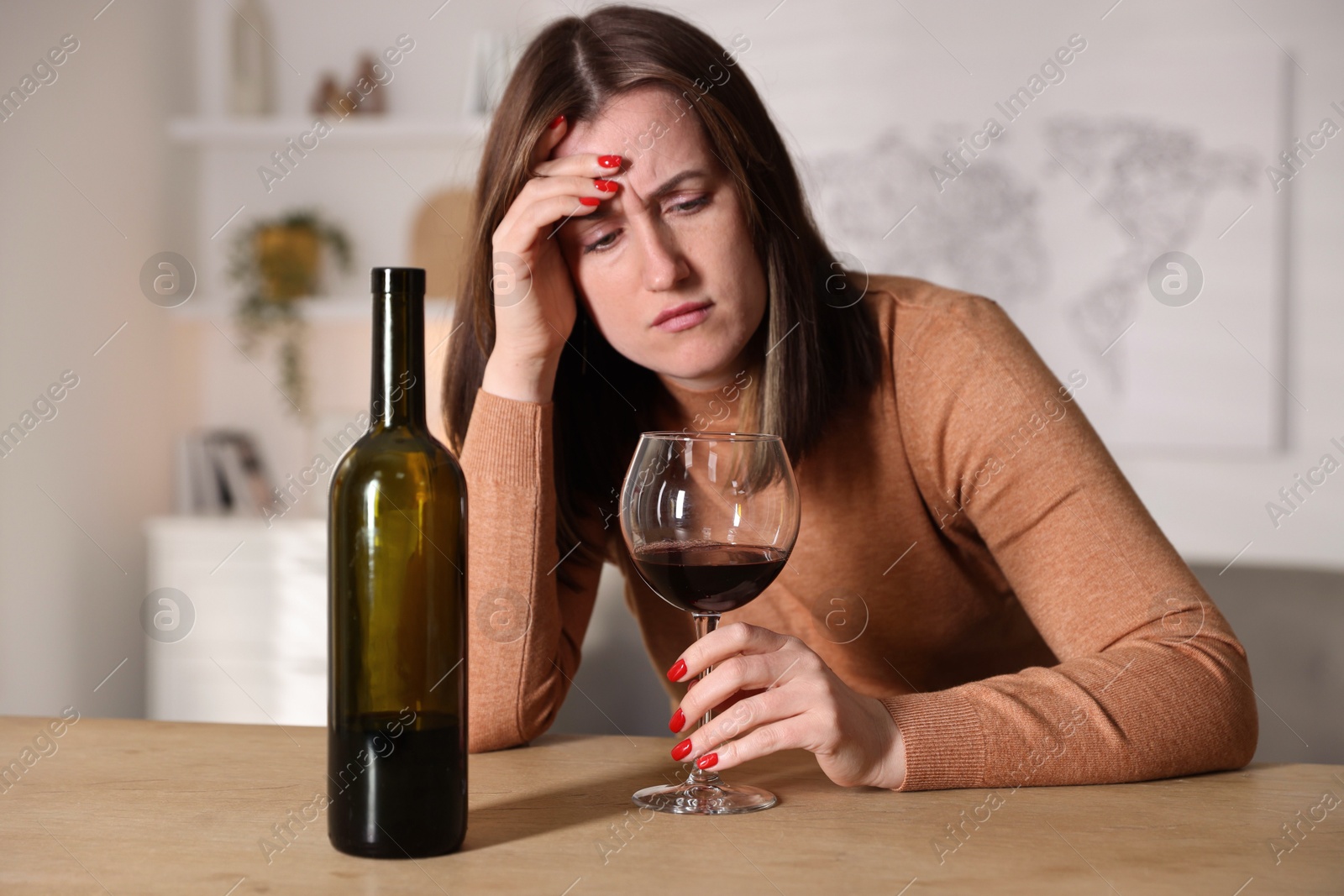 Photo of Alcohol addiction. Miserable woman with wine at table indoors