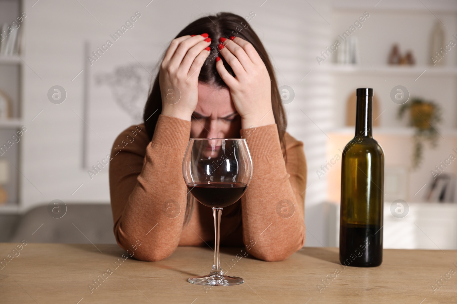 Photo of Alcohol addiction. Miserable woman with wine at table indoors