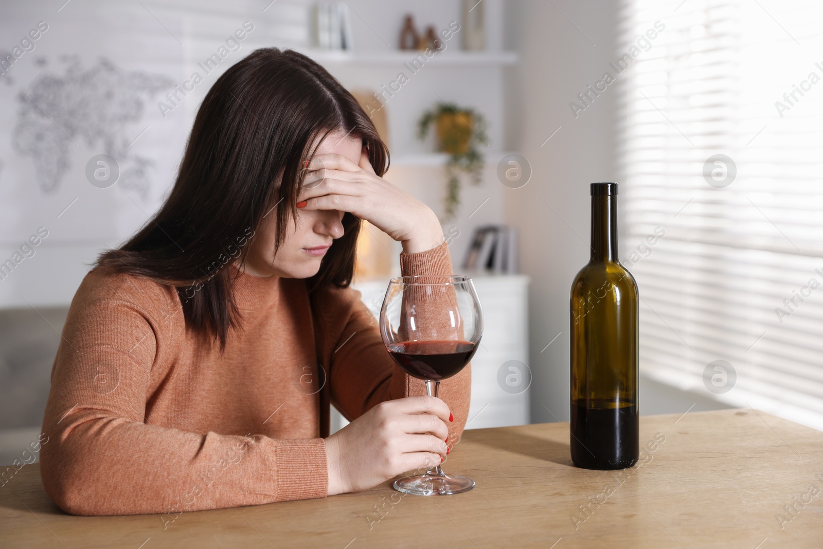 Photo of Alcohol addiction. Miserable woman with wine at table indoors, selective focus