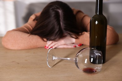 Photo of Alcohol addiction. Miserable woman with wine at table indoors, selective focus