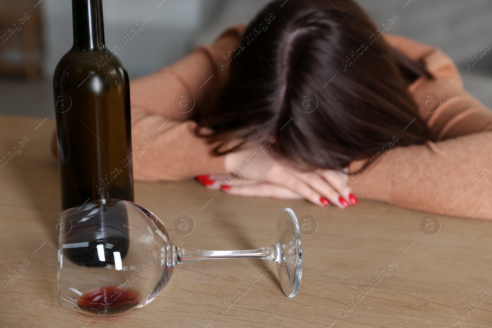 Photo of Alcohol addiction. Miserable woman with wine at table indoors, selective focus