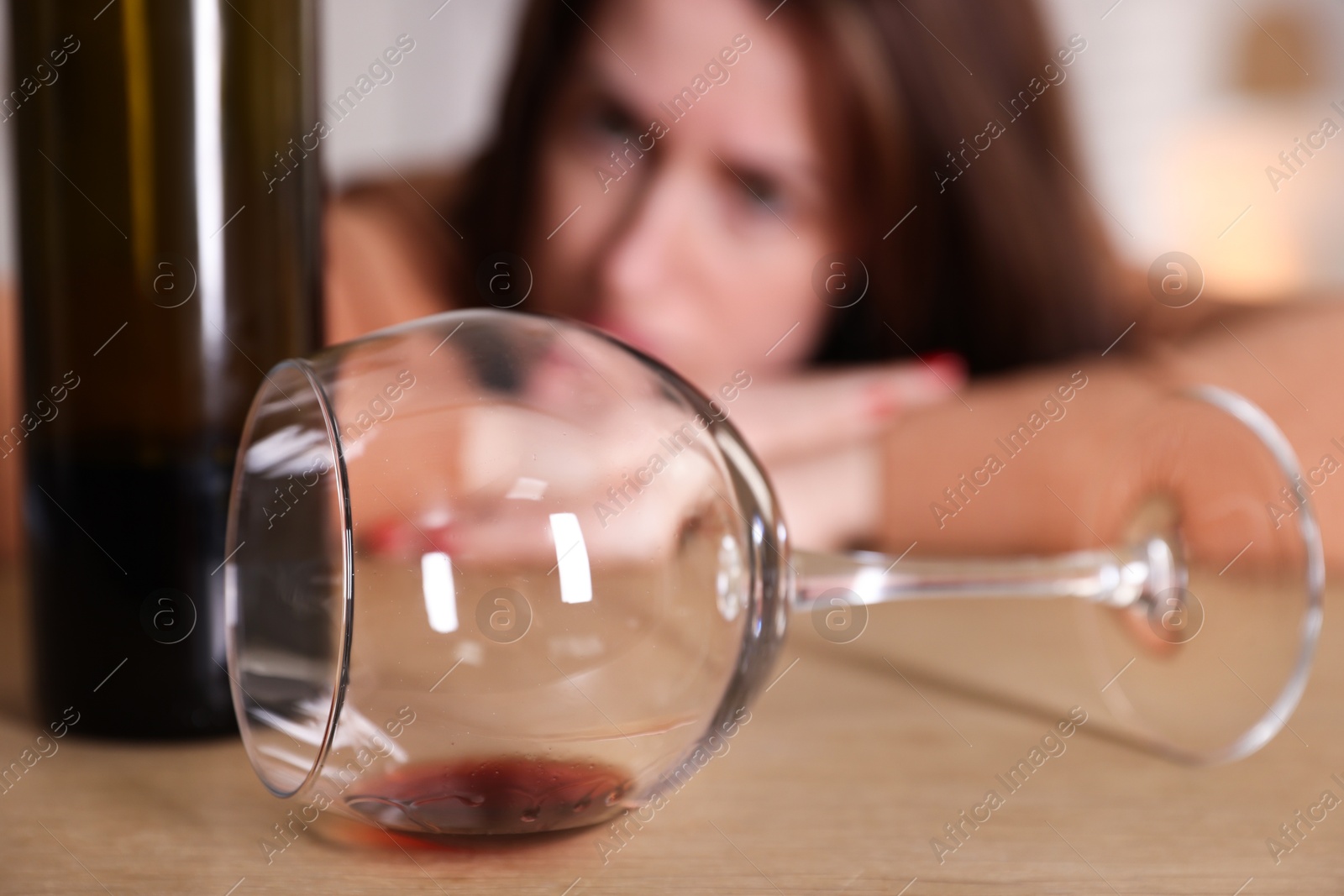 Photo of Alcohol addiction. Miserable woman with wine at table indoors, selective focus