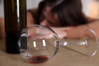 Photo of Alcohol addiction. Miserable woman with wine at table indoors, selective focus