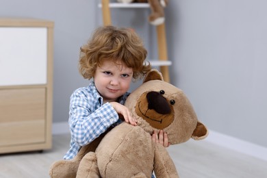 Photo of Resentful little boy with teddy bear indoors