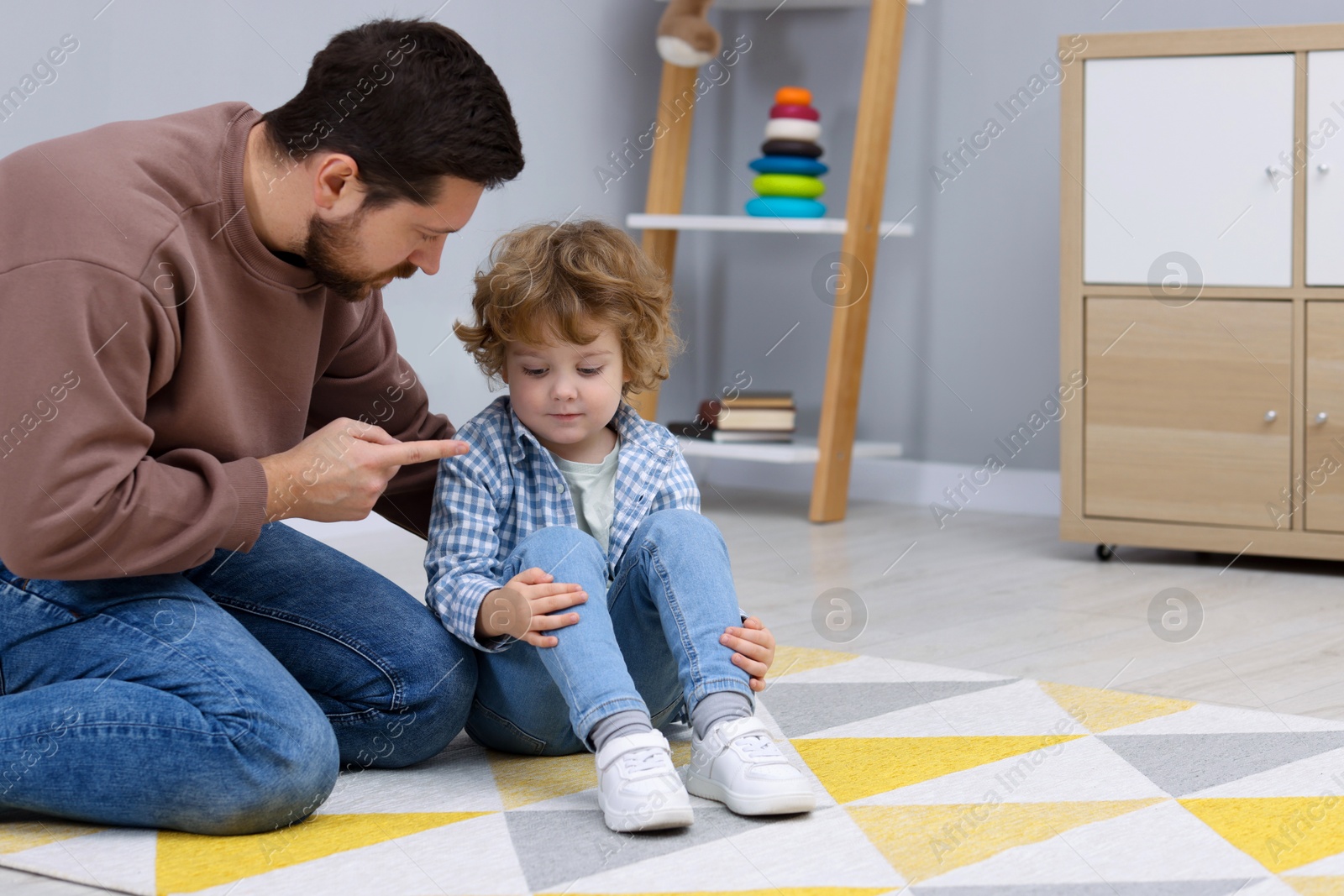 Photo of Resentful little boy and his father arguing at home, space for text