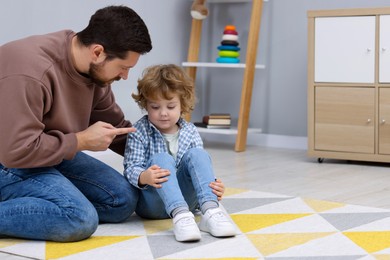 Photo of Resentful little boy and his father arguing at home, space for text