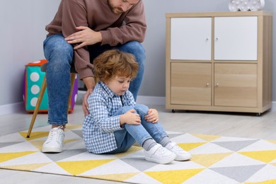 Photo of Resentful little boy and his father arguing at home, space for text