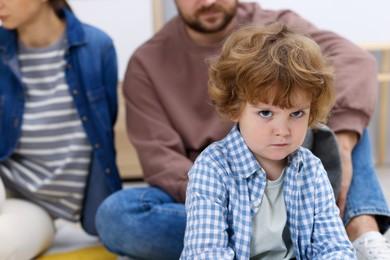 Photo of Resentful little boy and his parents arguing at home