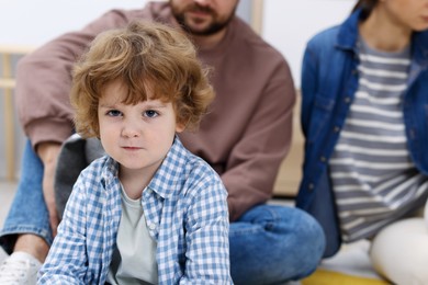 Photo of Resentful little boy and his parents arguing at home