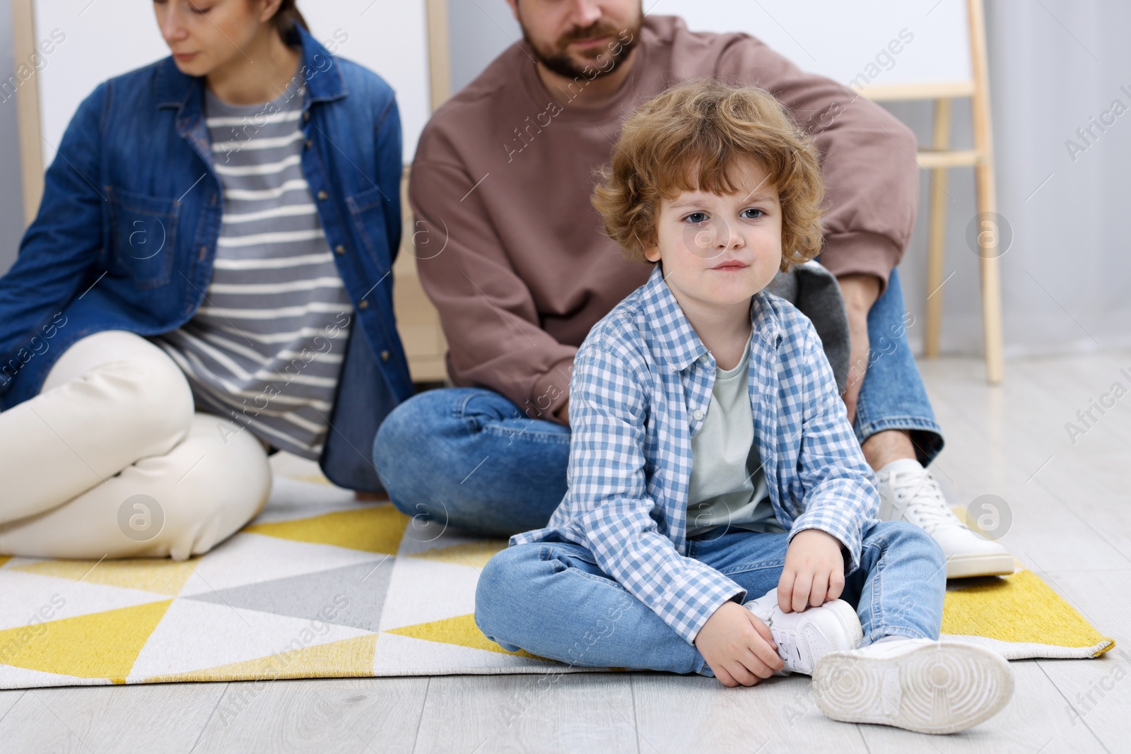 Photo of Resentful little boy and his parents arguing at home