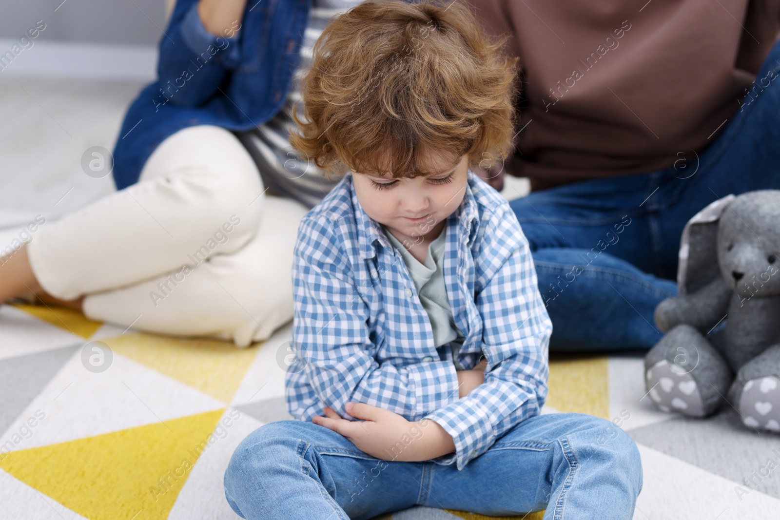 Photo of Resentful little boy and his parents arguing at home