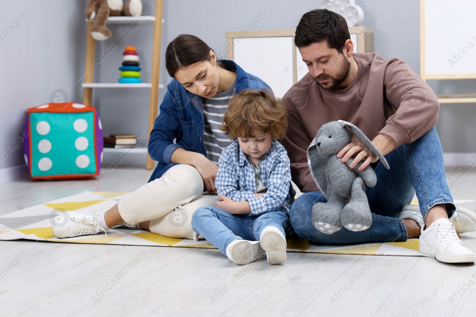 Photo of Resentful little boy and his parents arguing at home