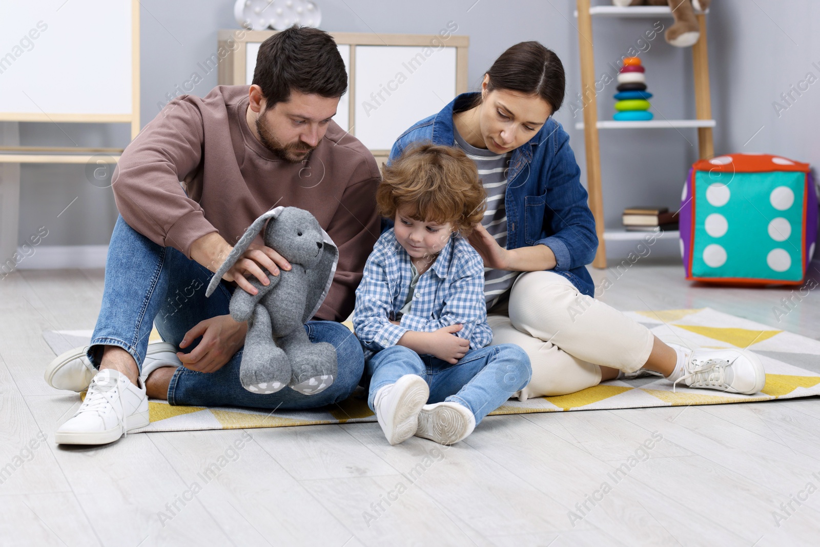 Photo of Resentful little boy and his parents arguing at home