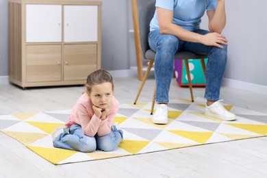 Photo of Resentful little girl and her father at home. Family dispute