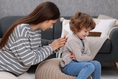 Photo of Resentful little boy and his mother arguing at home