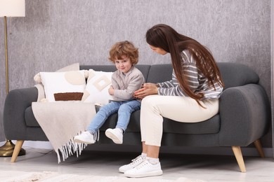 Photo of Resentful little boy and his mother arguing at home