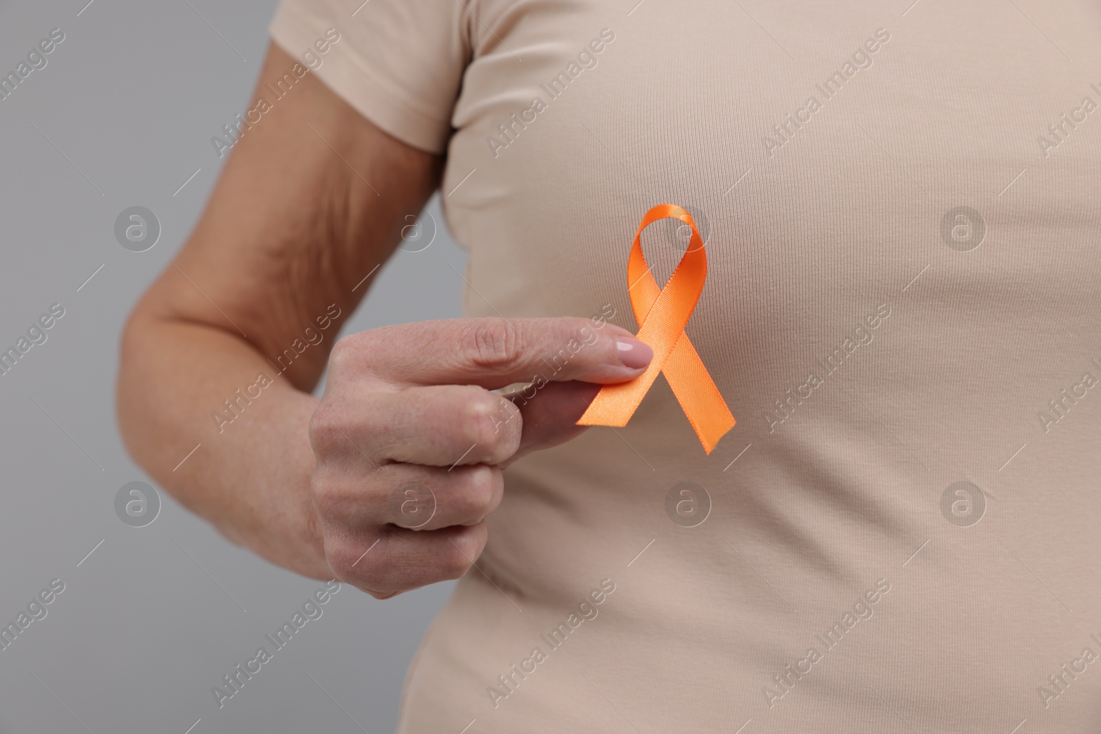 Photo of Multiple Sclerosis awareness. Woman with orange ribbon on light grey background, closeup