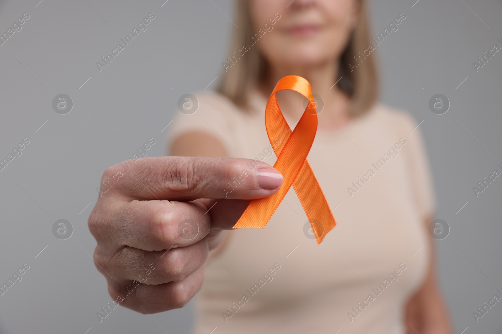 Photo of Multiple Sclerosis awareness. Woman with orange ribbon on light grey background, closeup