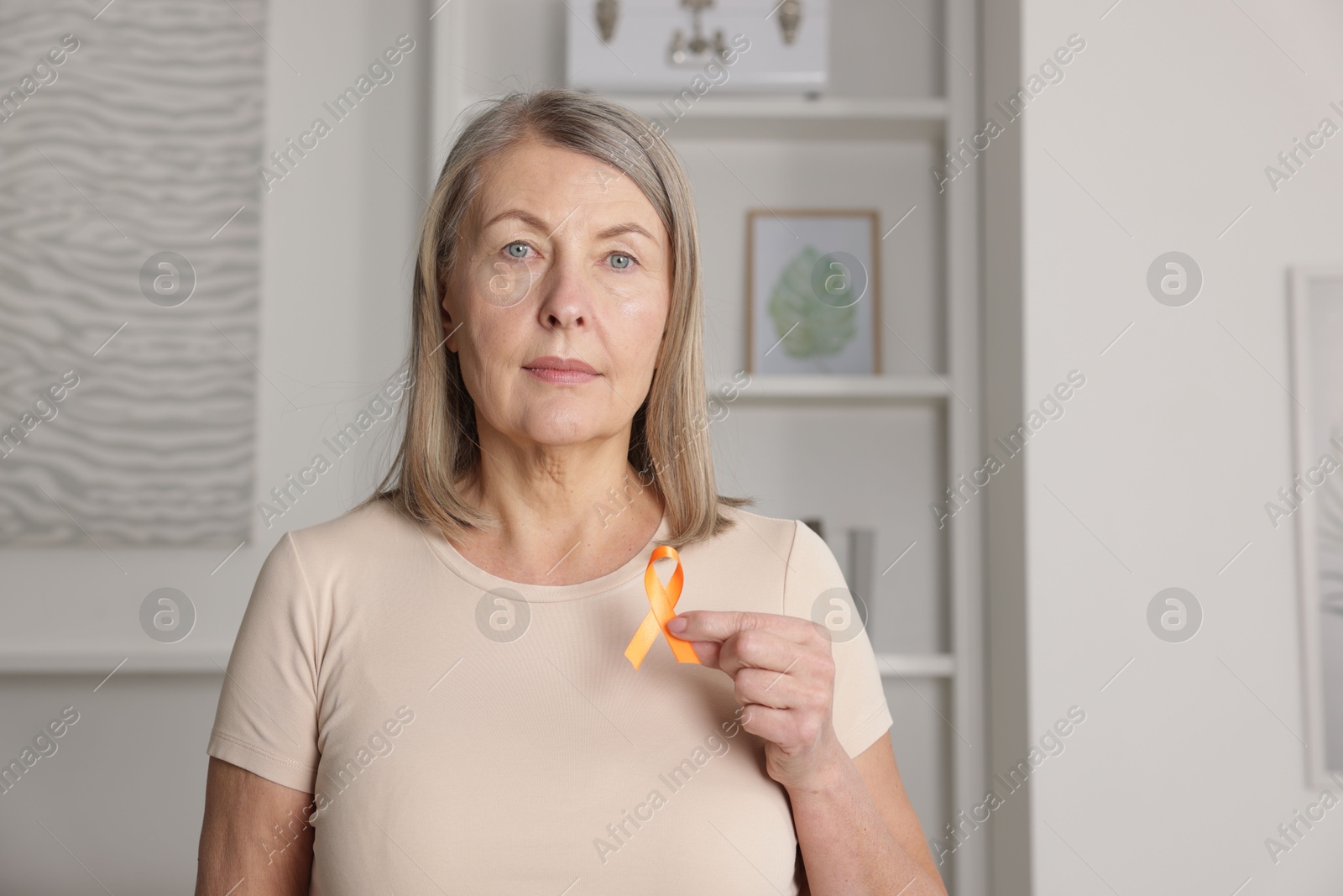 Photo of Multiple Sclerosis awareness. Woman with orange ribbon at home