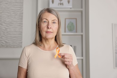 Photo of Multiple Sclerosis awareness. Woman with orange ribbon at home