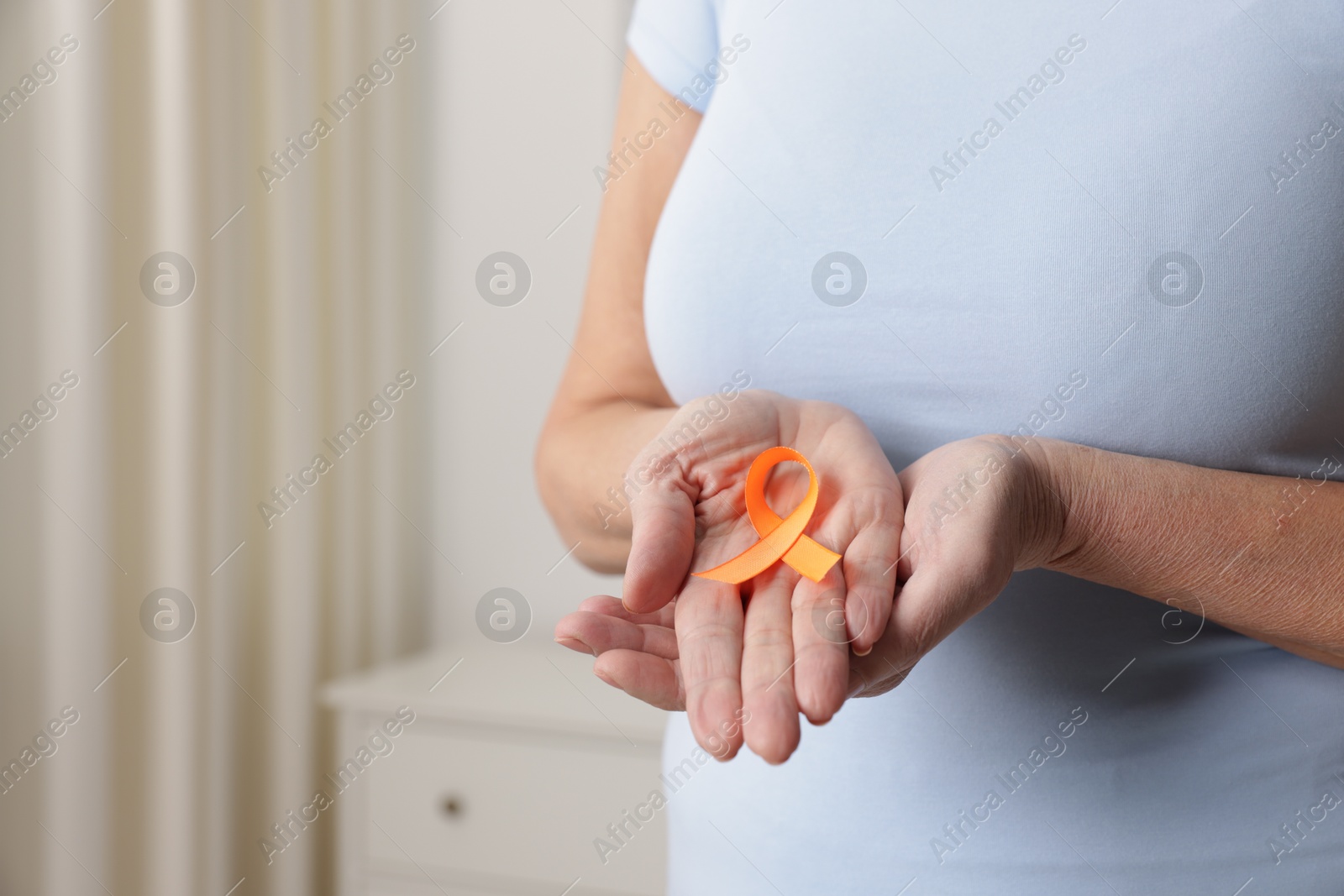 Photo of Multiple Sclerosis awareness. Woman with orange ribbon at home, closeup