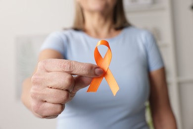 Photo of Multiple Sclerosis awareness. Woman with orange ribbon at home, closeup