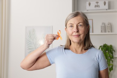 Photo of Multiple Sclerosis awareness. Woman with orange ribbon at home