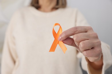 Photo of Multiple Sclerosis awareness. Woman with orange ribbon at home, closeup