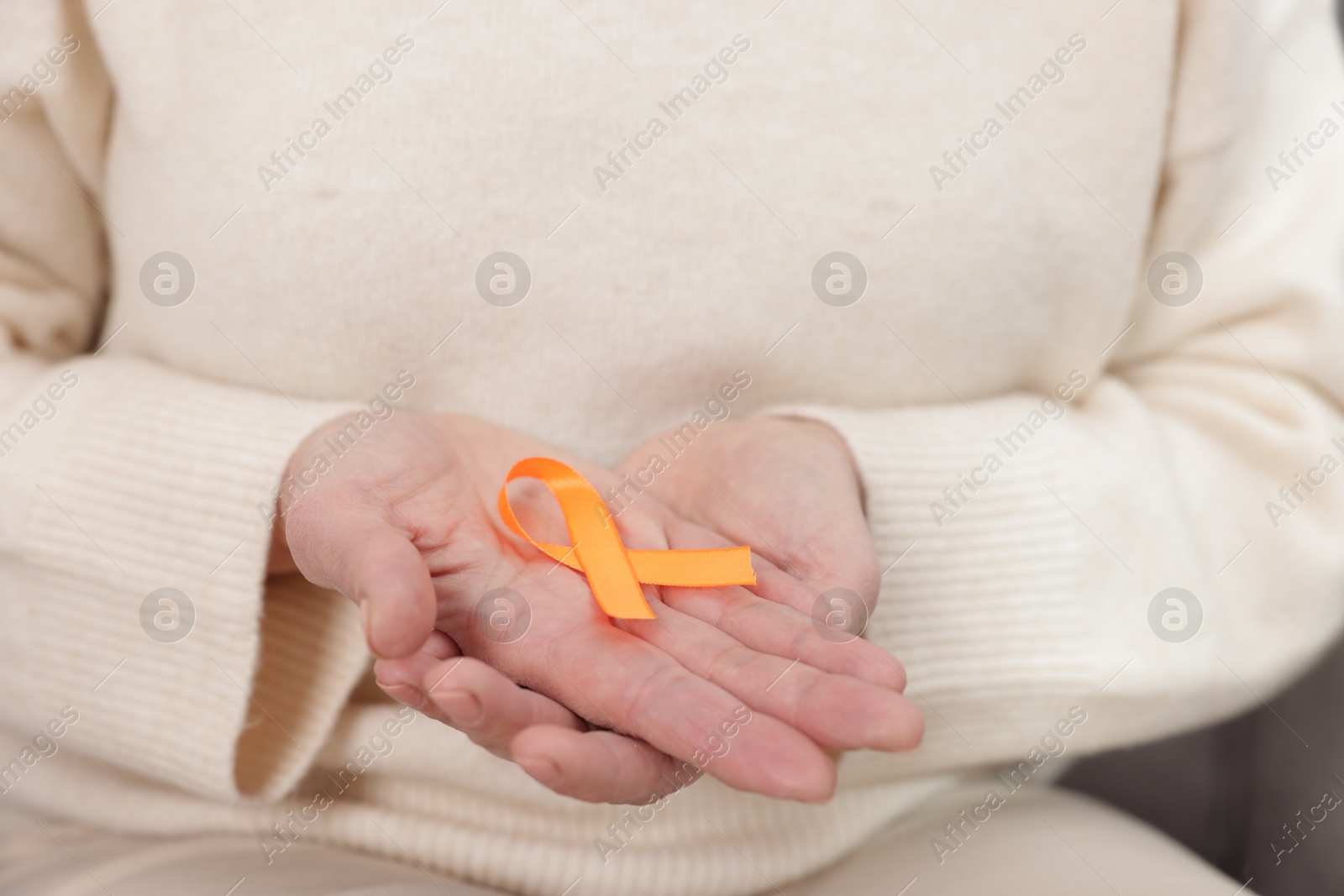 Photo of Multiple Sclerosis awareness. Woman with orange ribbon at home, closeup